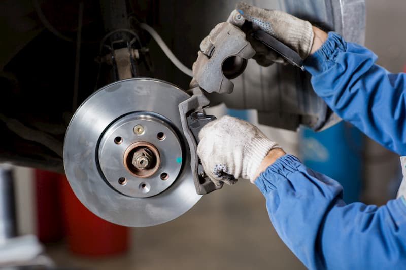 Brand new brake disc on car in a garage. Auto mechanic repairing.